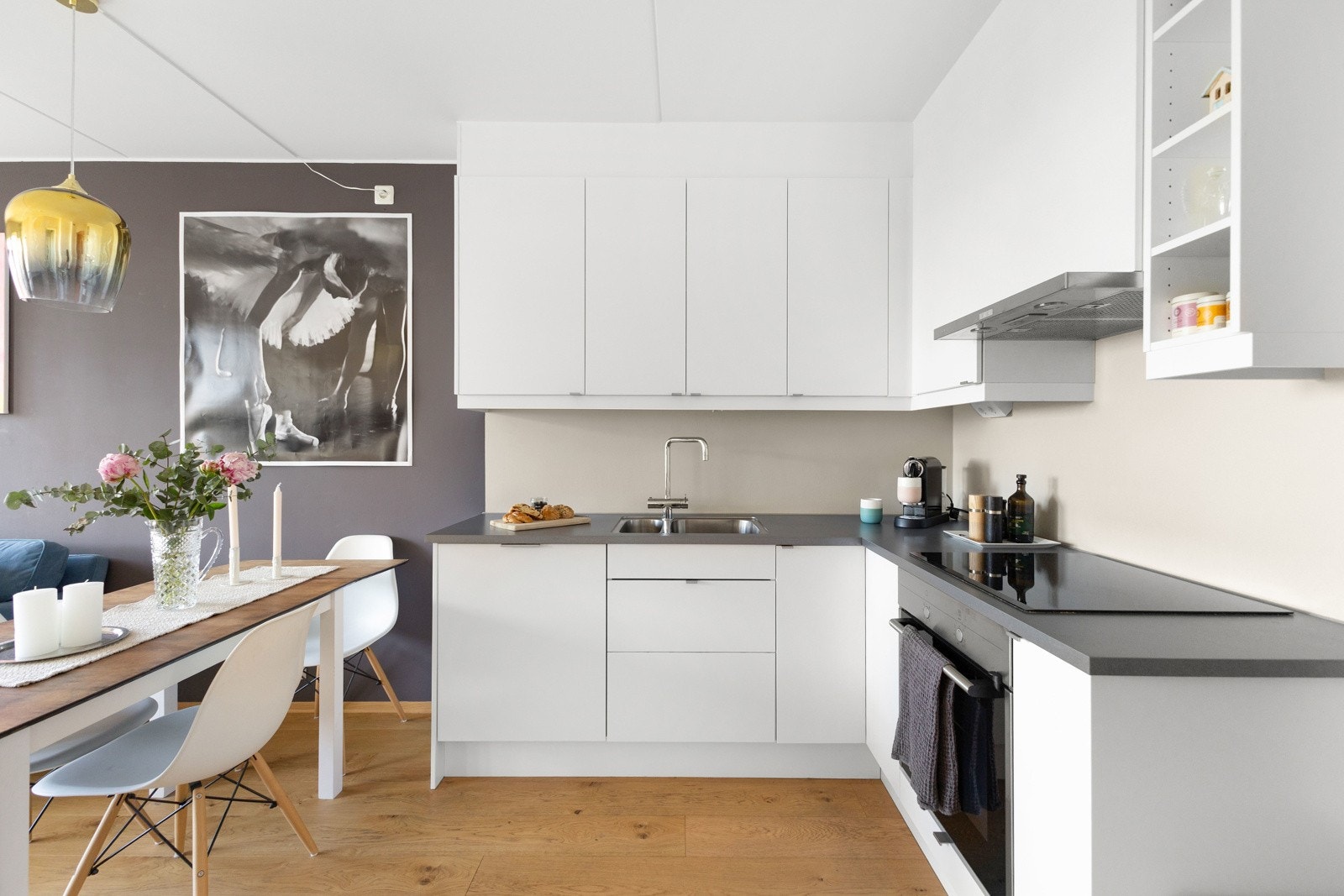 Kjøkkenet er både stilrent og funksjonelt med hvite, glatte fronter, mørk benkeplate og integrerte Siemens hvitevarer. Galleribilde