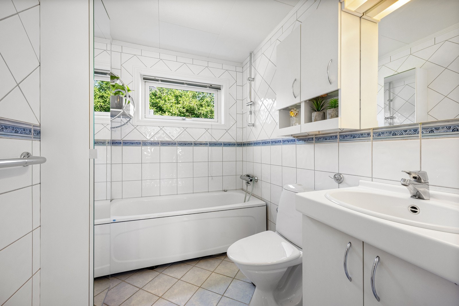 Pent flislagt bad med badekar, toalett og servant med underskap. Galleribilde