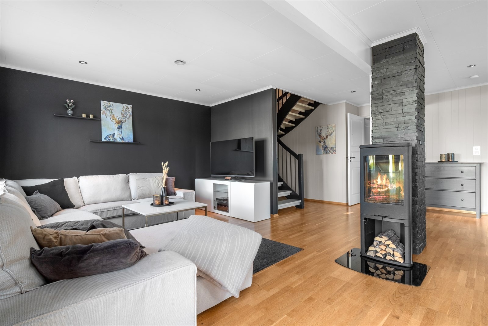 Stuekroken fremstår som både stilfull og innbydende, med en mørk kontrastvegg som tilfører rommet et moderne preg. Her er det god plass til både TV-løsning og en romslig sofagruppe. Galleribilde