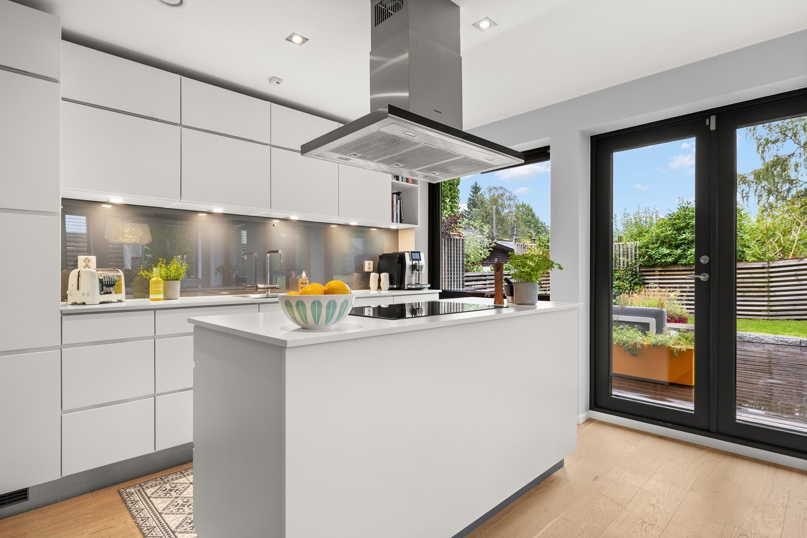 Lyst og pent kjøkken med utgang ut til skjermet terrasse Galleribilde