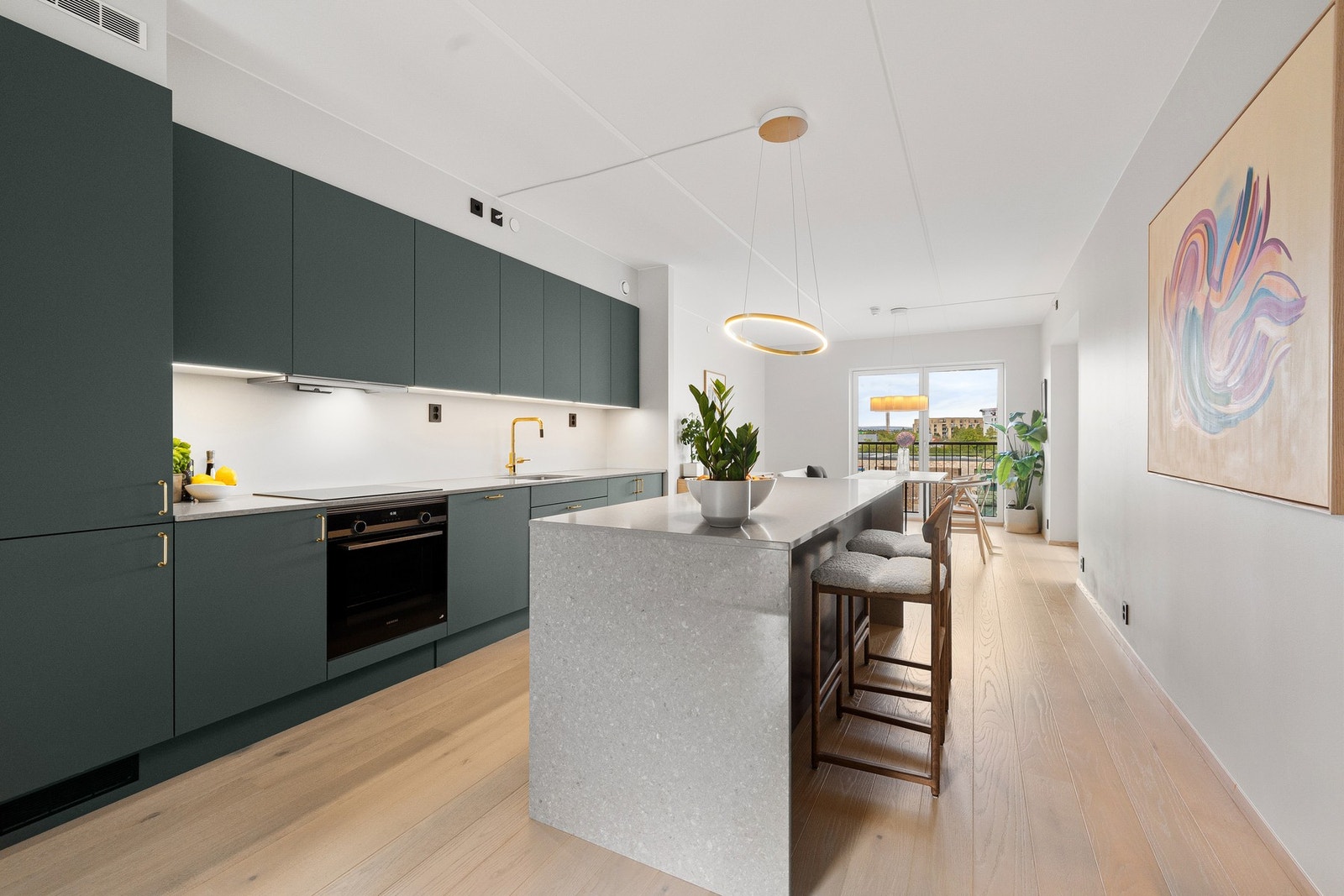 Kjøkkenet er plassert som et naturlig midtpunkt i oppholdsrommet, og fungerer som et sosialt samlingspunkt i hjemmet. Galleribilde