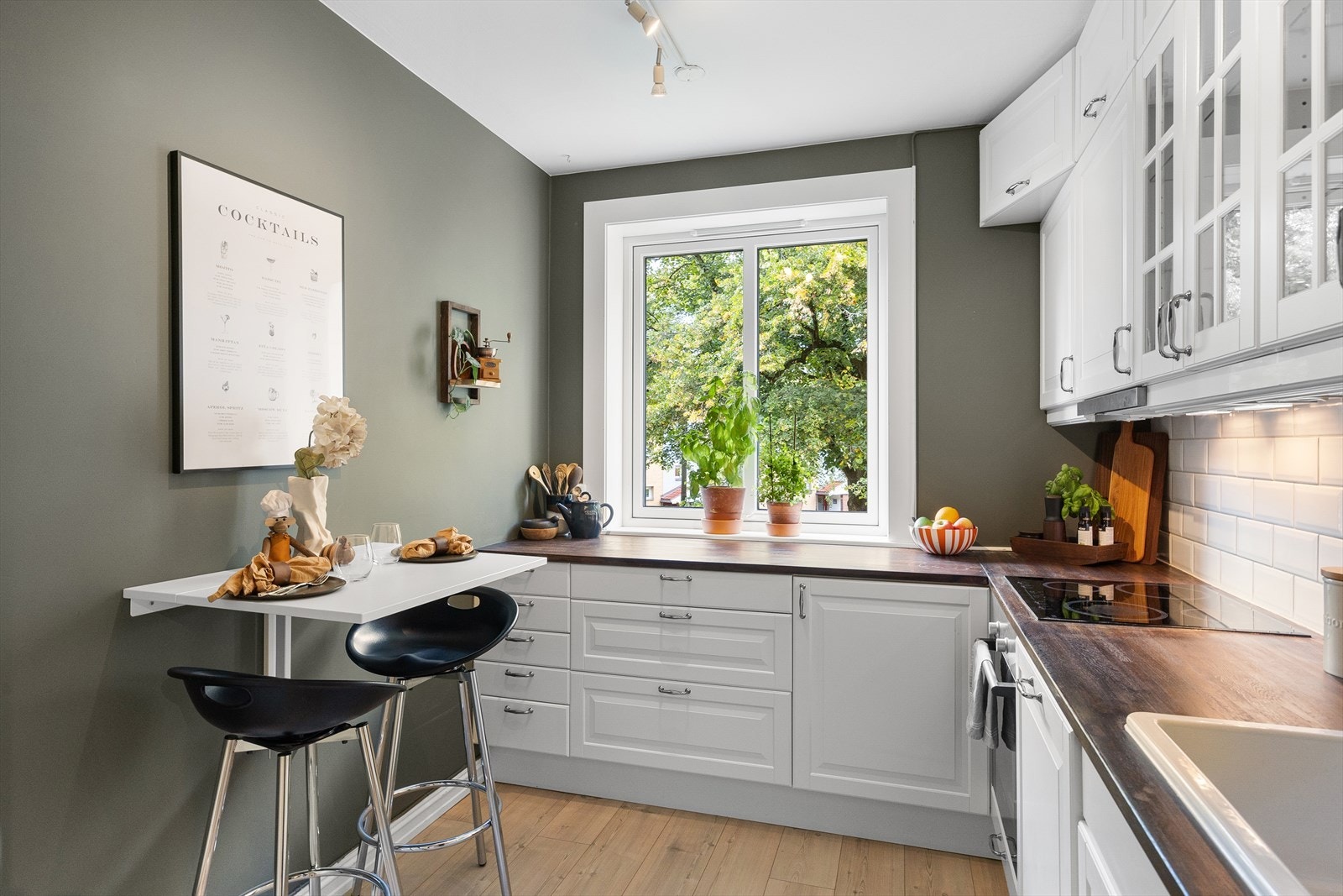 Moderne IKEA-kjøkken fra 2012 med hvite profilerte fronter, heltre benkeplate og nedfelt porselensvask med ettgreps blandebatteri i krom med dusjfunksjon. Galleribilde