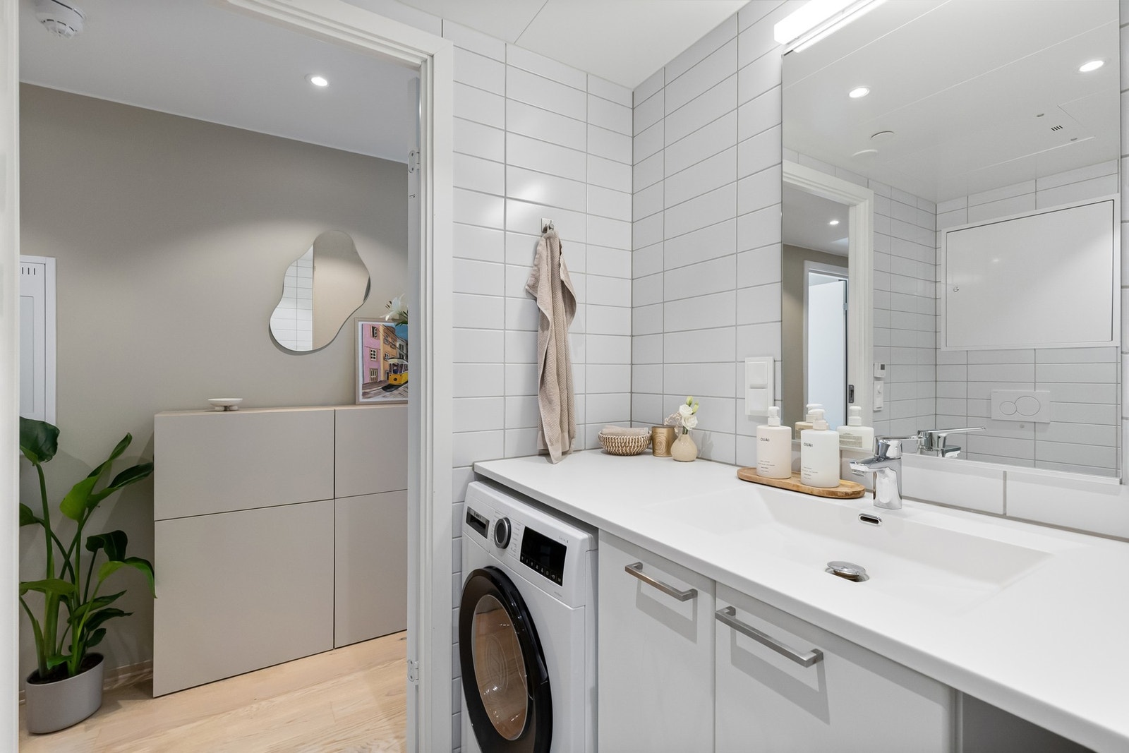 Plasstilpasset baderomsinnredning med helstøpt benkeplate med servant med underskap for oppbevaring og smart nisje for vaskemaskin. Galleribilde