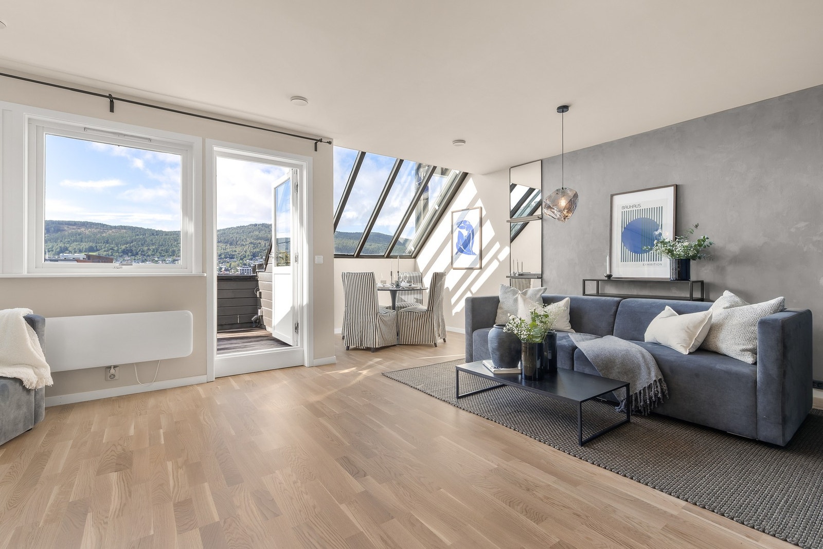 Stuen fremstår stilfull med parkettgulv og slette, lysmalte flater på vegger og i himling. En kontrastvegg med grå kalkmaling gir rommet et moderne preg Galleribilde