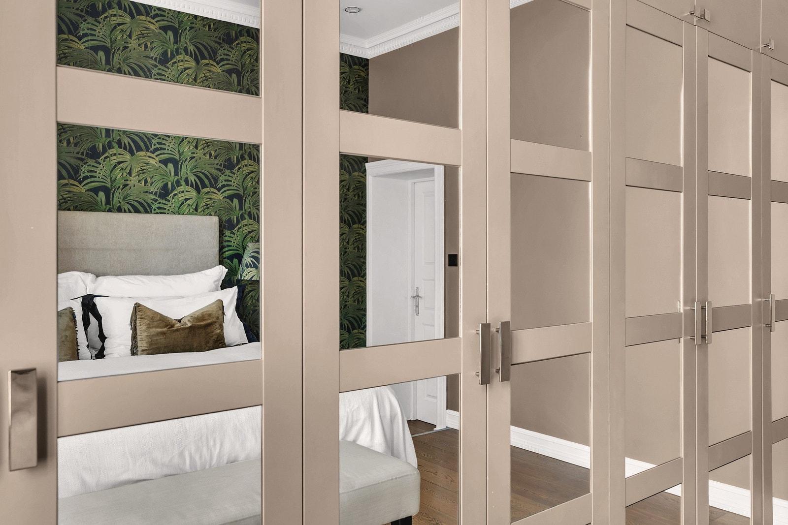 Langs hele veggen er det plassbygd garderobeløsning med speilfronter som gir både rikelig oppbevaring og en følelse av ekstra romfølelse. Galleribilde