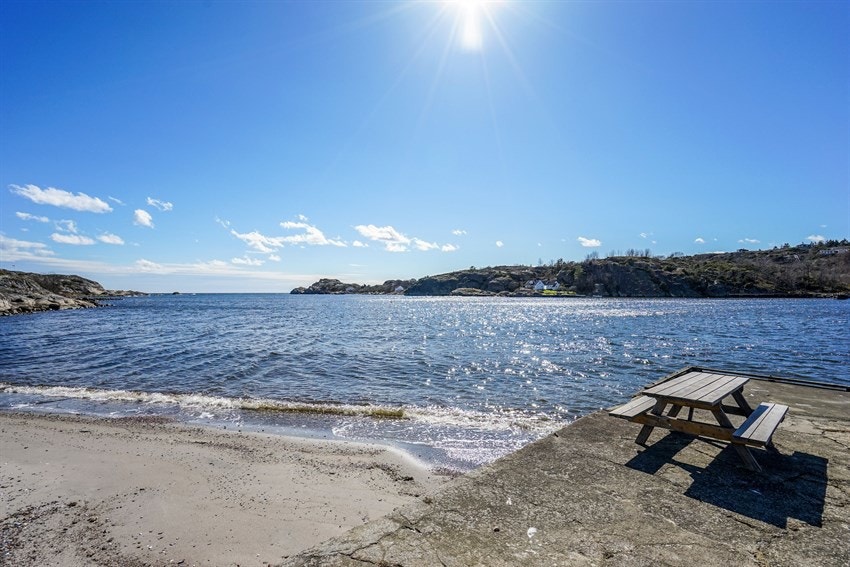Stranda ligger ca.1 minutt med bil fra hytta og det er godt med parkeringsplasser. Her ligger også båtplassen. Stranda har både langgrunne og dypt vann, fint for både voksne og barn. På Steinbrygga fiskes det også krabber. Galleribilde