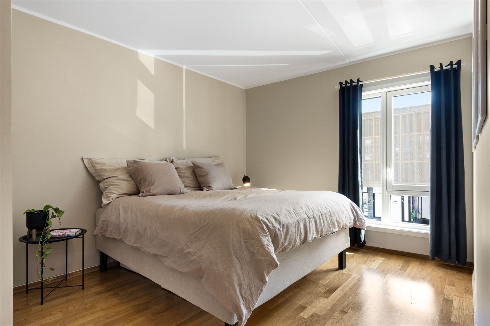 Et lyst og delikat soverom med god plass til dobbeltseng Galleribilde