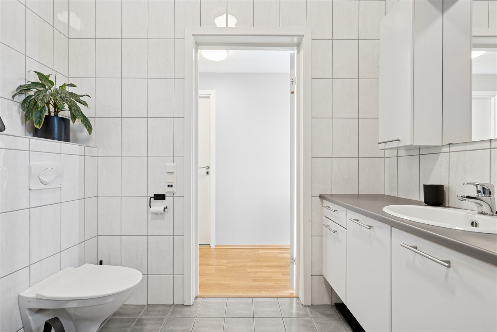 Badet er tidløst med grå gulvfliser m/gulvvarme under og hvite veggfliser Galleribilde