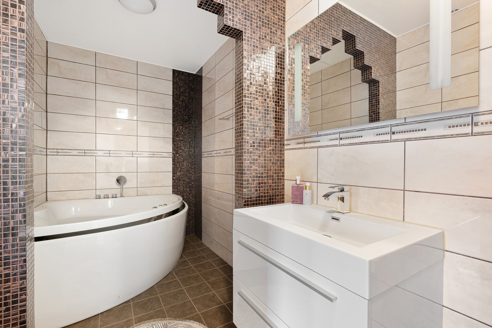 Fine farger på flis, speil med integrert lys, opplegg for vaskemaskin og boblebadekar på badet. Galleribilde