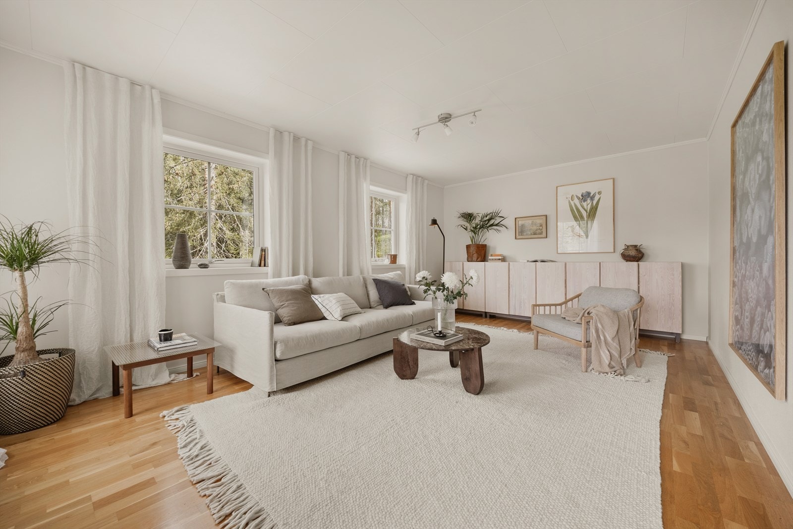 Romslig stue med parkett på gulv, malt strie på veggene og Takess-plater i himlingen. Galleribilde