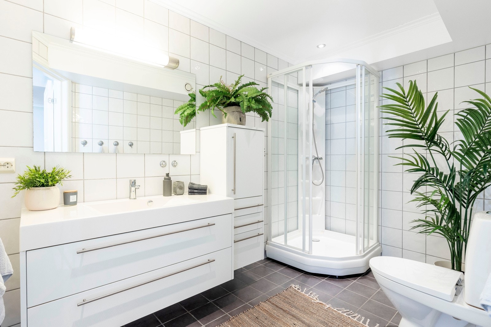 Lyst og delikat bad som innbyr til rekreasjon og velbehag. Badet har gulvflis, veggflis og lysmalt himling med downlights. Badet har sanitærutstyr som toalett, dusjkabinett, vask og opplegg til vaskemaskin. Galleribilde