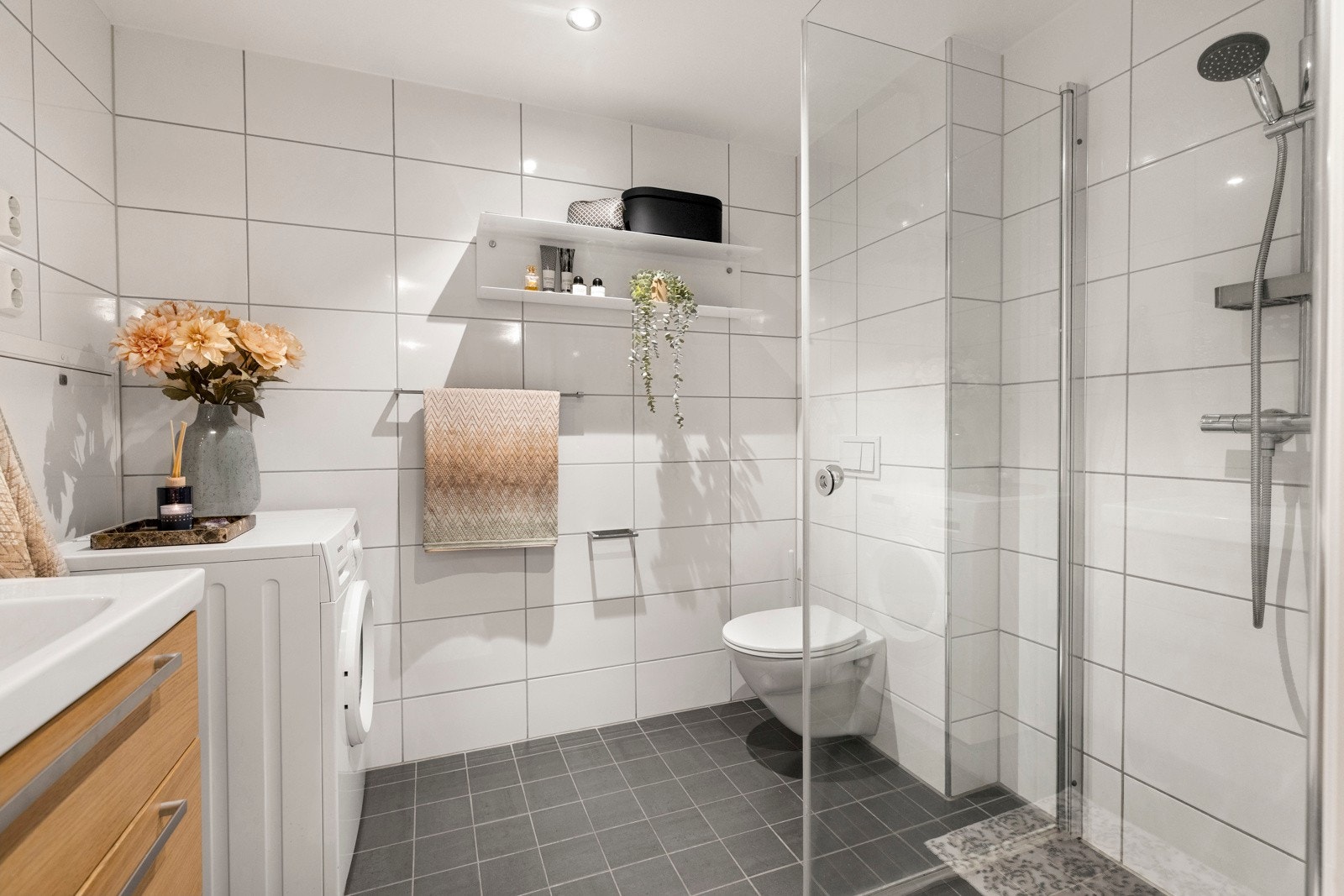 Rommet er utstyrt med innredning med nedfelt servant, vegghengt toalett, dusjhjørne med glassvegger og opplegg for vaskemaskin. Galleribilde