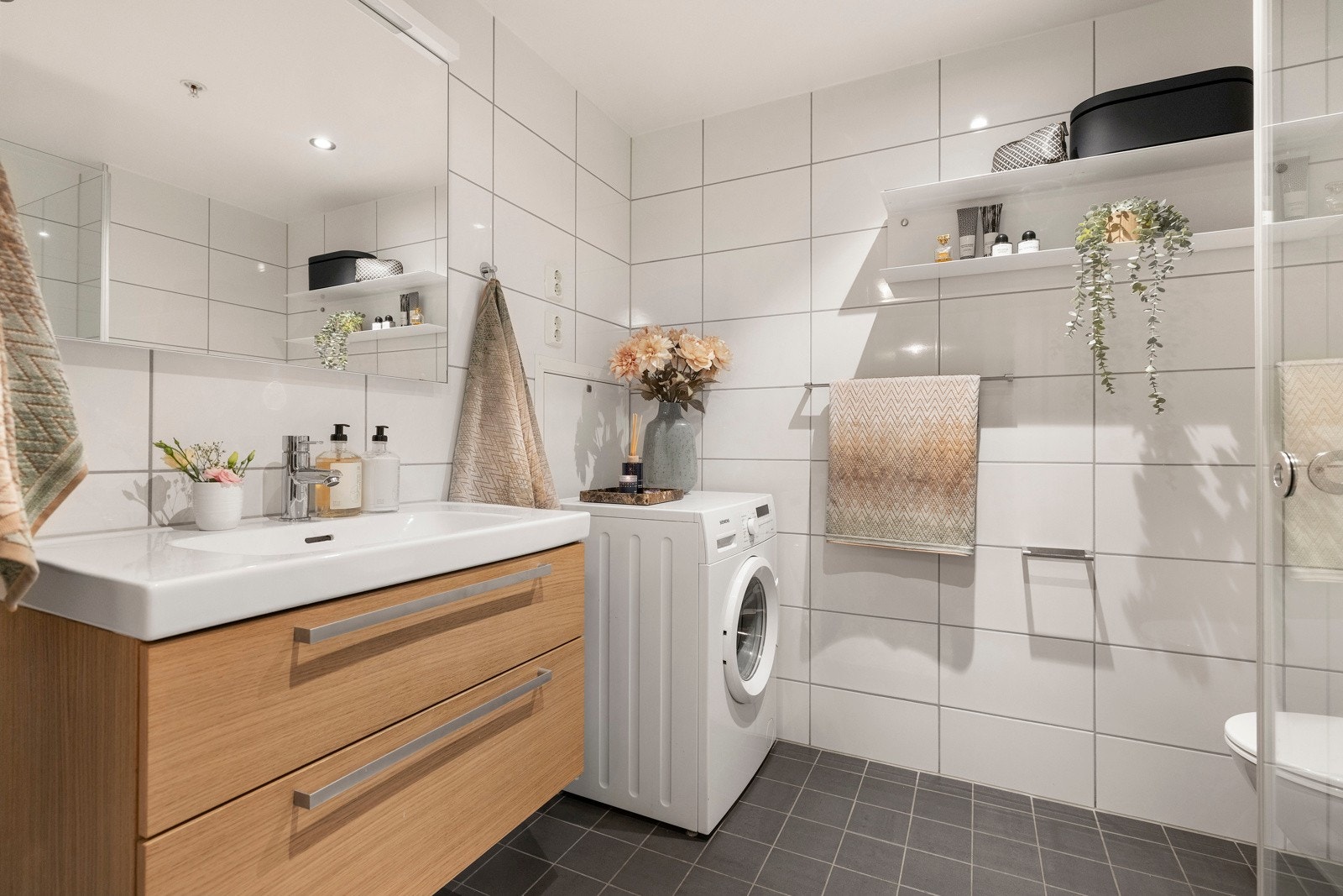 Badet fremstår moderne og tidløst med flislagte vegger, malt tak og flislagt gulv med elektriske varmekabler som gir god komfort. Galleribilde