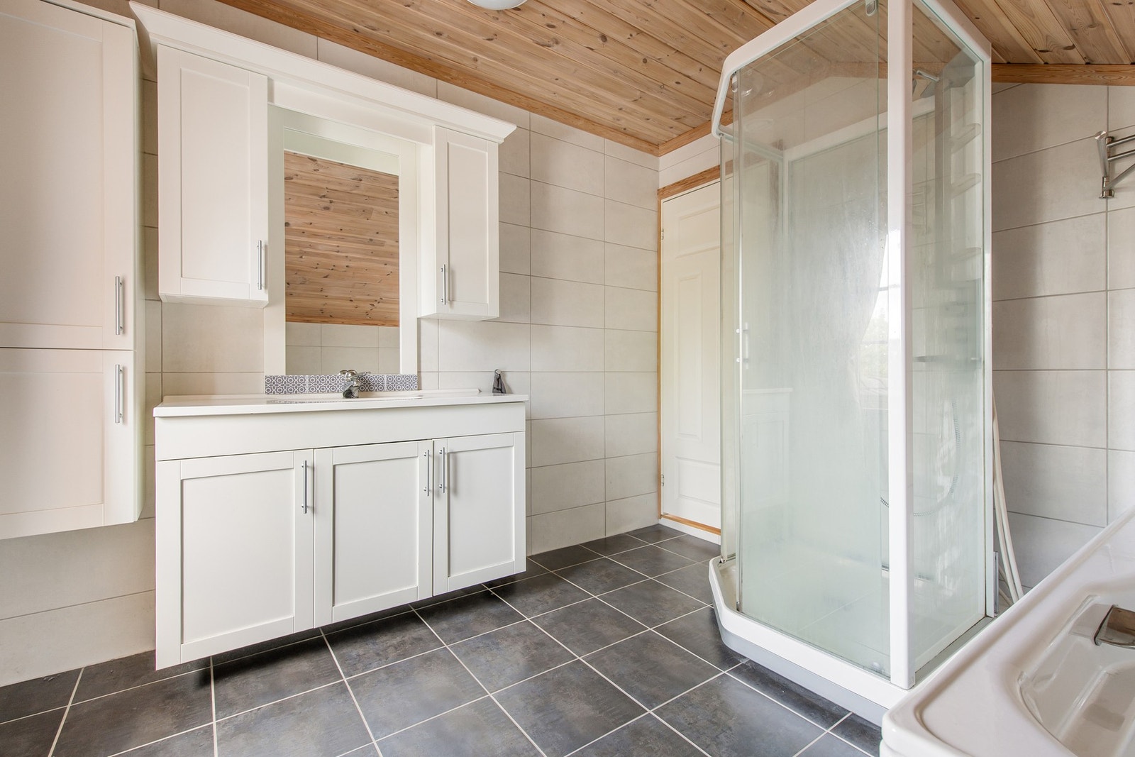 Badet består av toalett, servant, dusjkabinett og badekar. Galleribilde