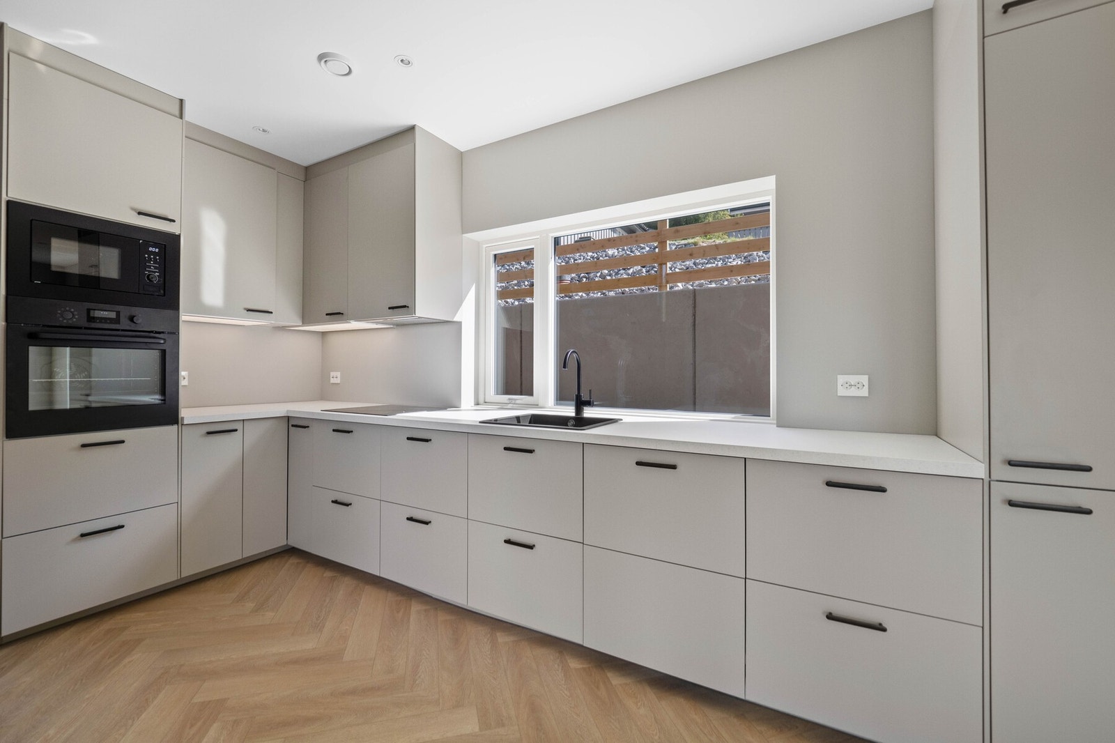 De glatte frontene på kjøkkeninnredningen har samme, delikate farge som veggene. Galleribilde