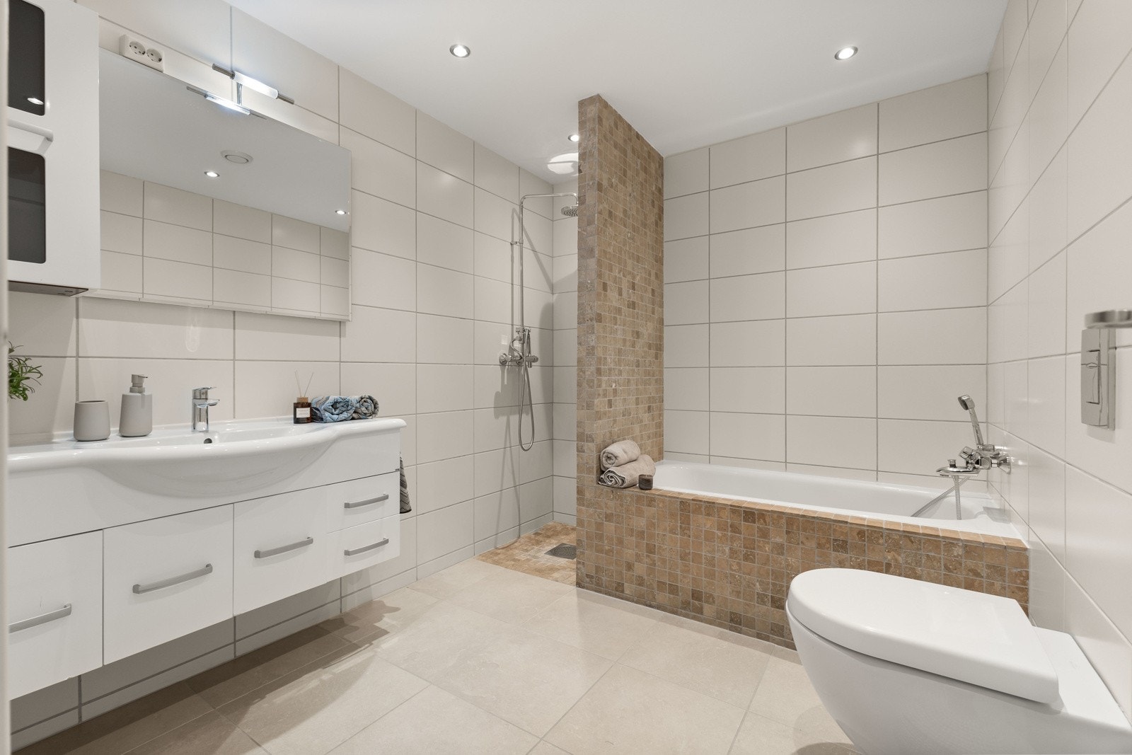 Boligen har et romslig bad med både dusj og innmurt badekar - perfekt for alt fra raske morgendusjer til avslappende kveldsbad. Galleribilde