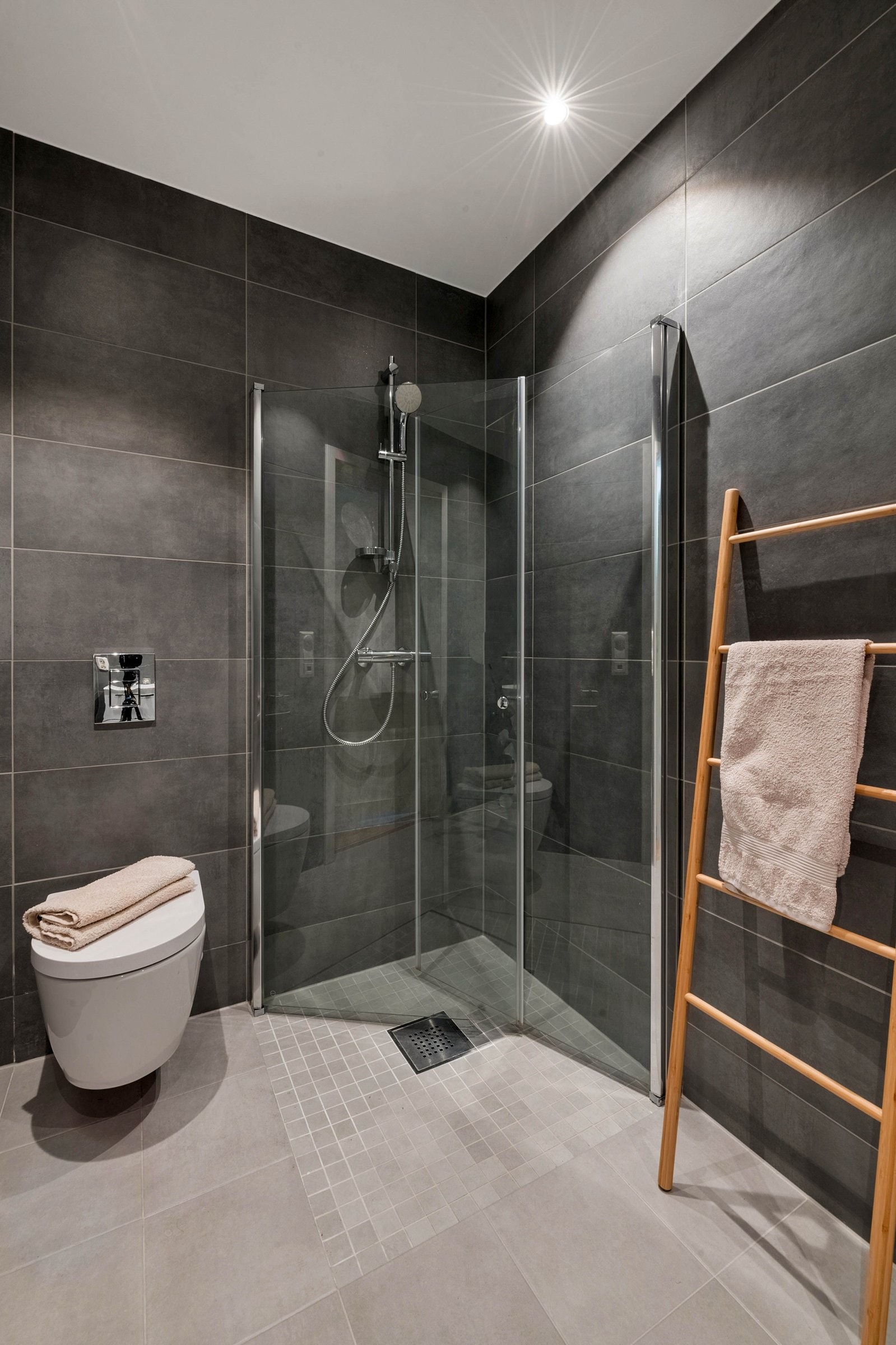 Badet er utstyrt med dusjhjørne og vegghengt toalett. Galleribilde