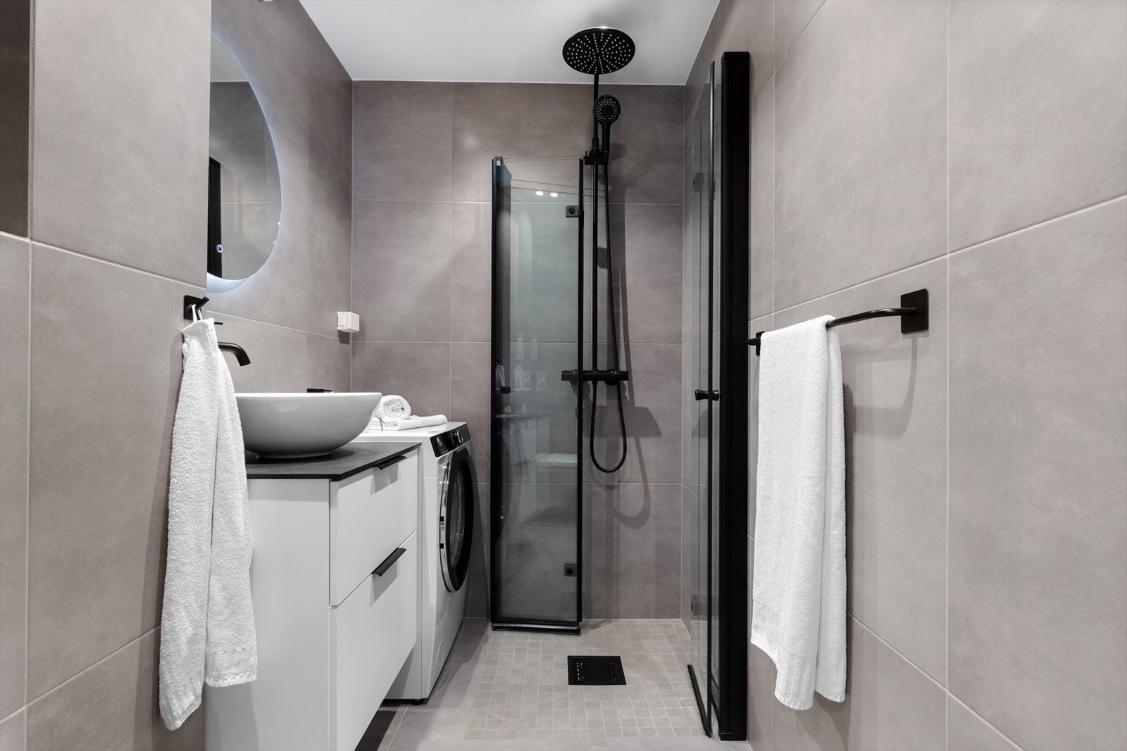 Badet ble pusset opp av fagfolk i 2021 med store, grå fliser og downlights i tak. Innredningen består av servant med skuffer og et rundt speil med belysning. Galleribilde