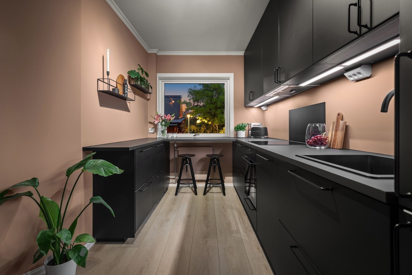 Selve kjøkkenet er stilig og topp moderne. Innredningen har glatte, sorte fronter og mørk grå, laminert benkeplate med nedfelt oppvaskkum. Galleribilde