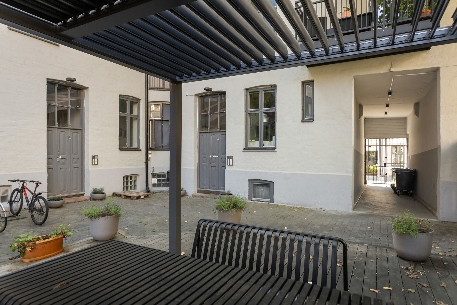 Skjermet og pent opparbeidet bakgård med terrasseplatting og sykkelparkering. Galleribilde