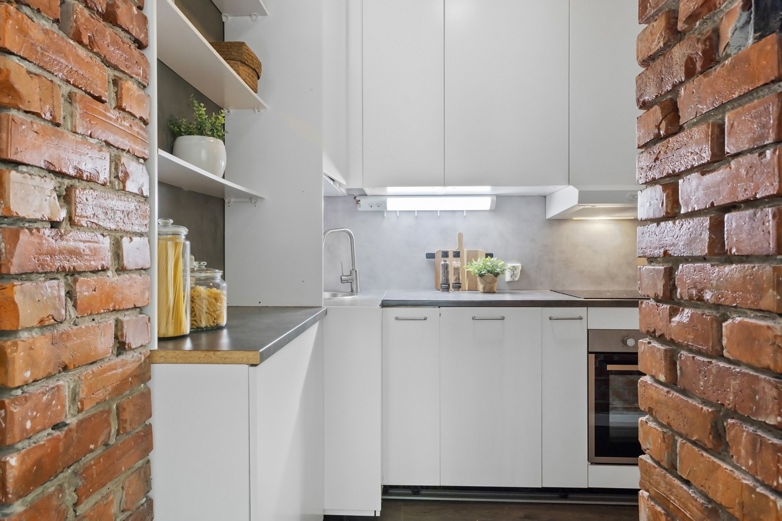 Kjøkkenet er arealeffektivt plassert i tilknytning til gangarealet og har en moderne innredning fra 2019. Denne har hvite, glatte fronter med takoppforede skap, noen åpne hyller og benkeplate i grå laminat med nedfelt vaskekum i stål. Galleribilde