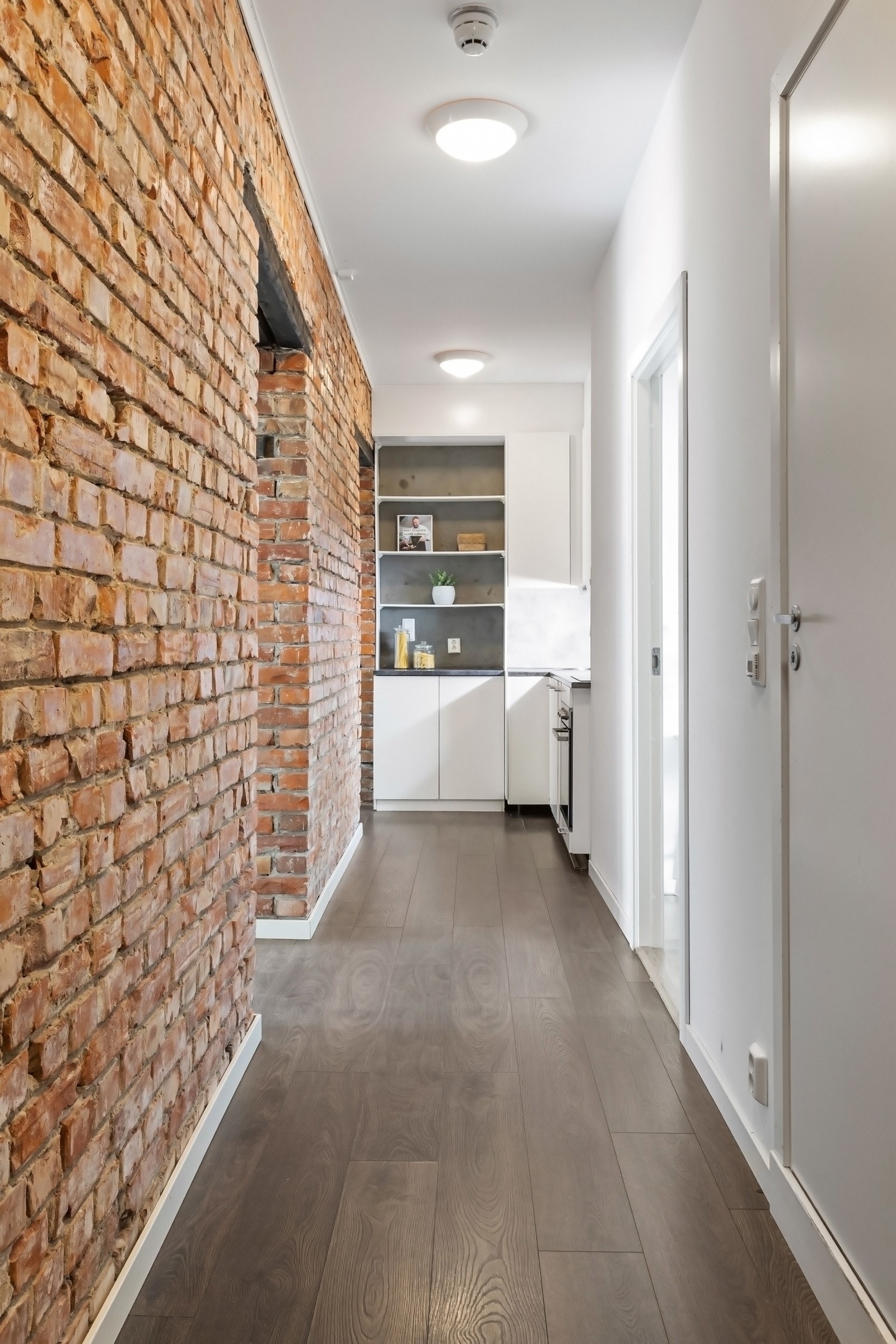 Den ene veggen i gangen er beholdt i naken tegl og gir et rustikk særpreg. Galleribilde