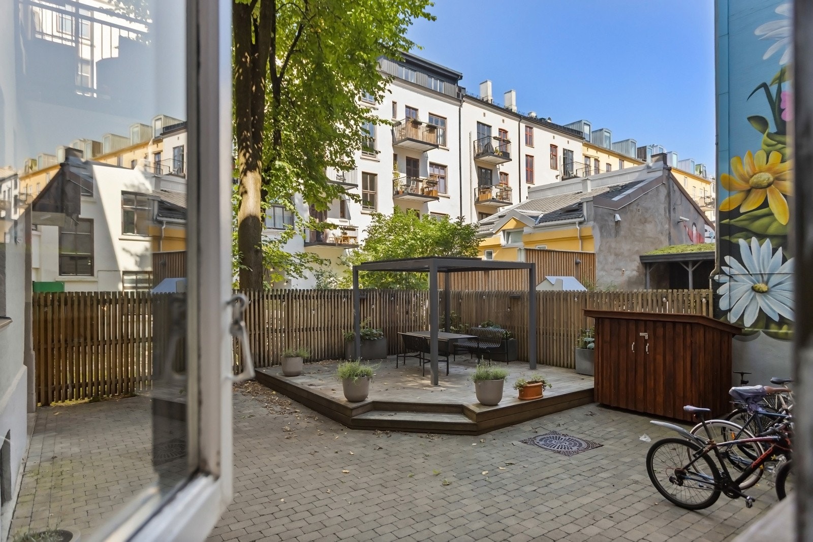 Skjermet og pent opparbeidet bakgård med terrasseplatting og sykkelparkering. Galleribilde