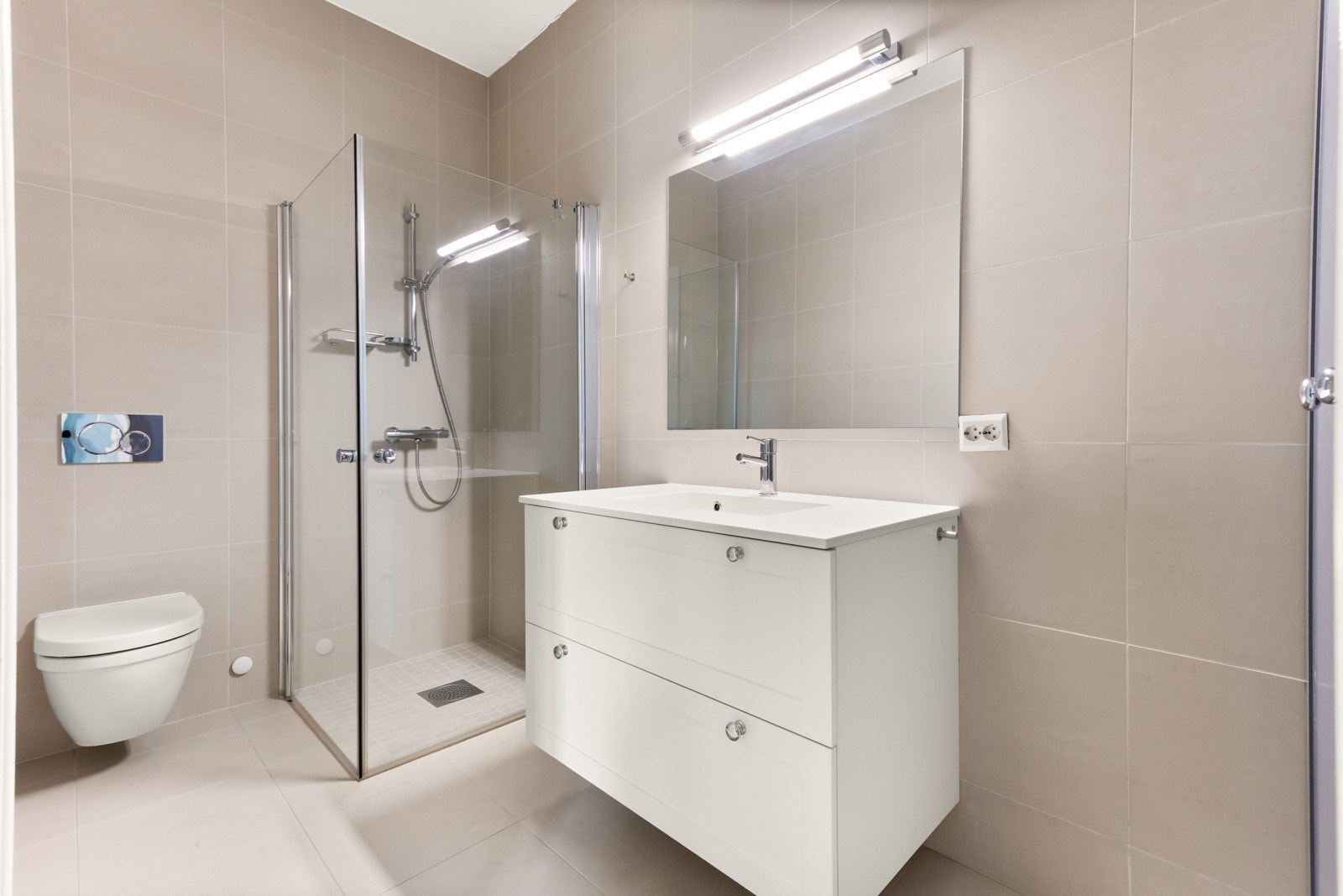 Badet er innredet med vegghengt toalett, servant nedfelt i innredning, dusjhjørne med svingbare glassdører og opplegg for vaskemaskin Galleribilde