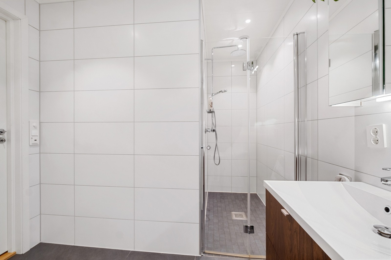 Det er dusjnisje m/takdusj, badekar, vegghengt toalett og baderomsinnredning Galleribilde