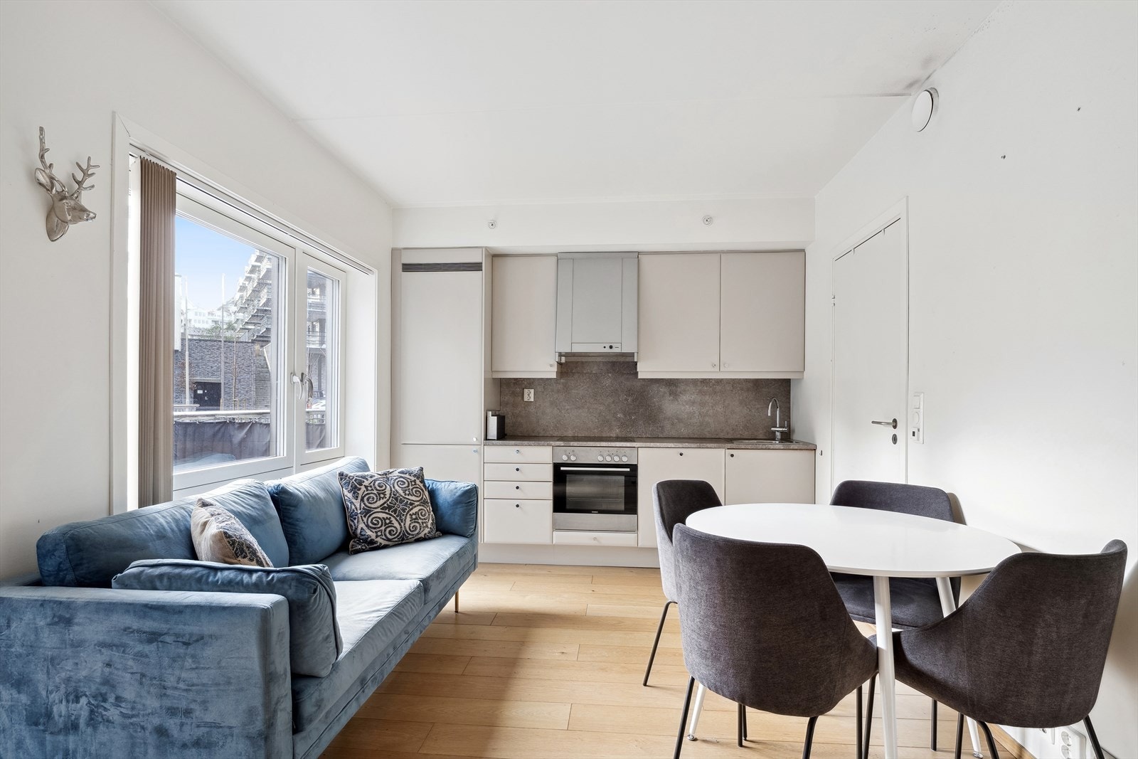 Stuen og kjøkkenet ligger i åpen løsning, og sammen danner de et lyst og fint allrom med luftig atmosfære. Dette understrekes med dagslyset som strømmer inn via store vindusflater og gjenspeiles i de lysmalte overflatene. Galleribilde