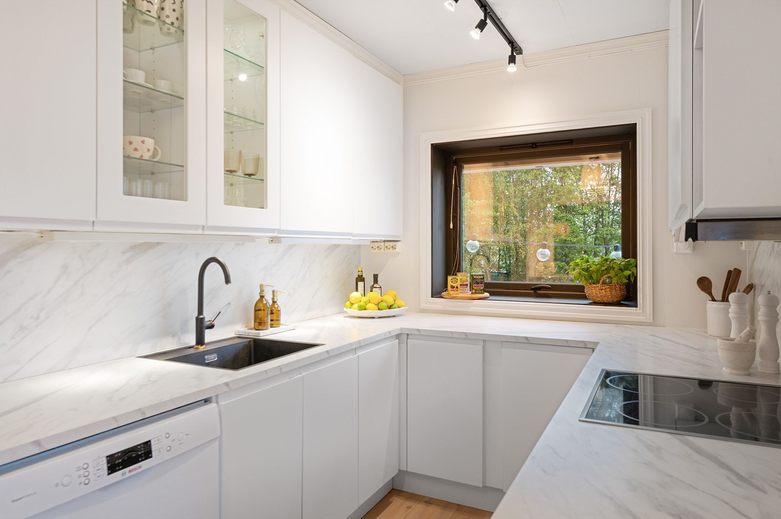 Stilig og moderne kjøkken med hvite, glatte fronter og svarte detaljer. Godt med skap- og benkeplass. Galleribilde