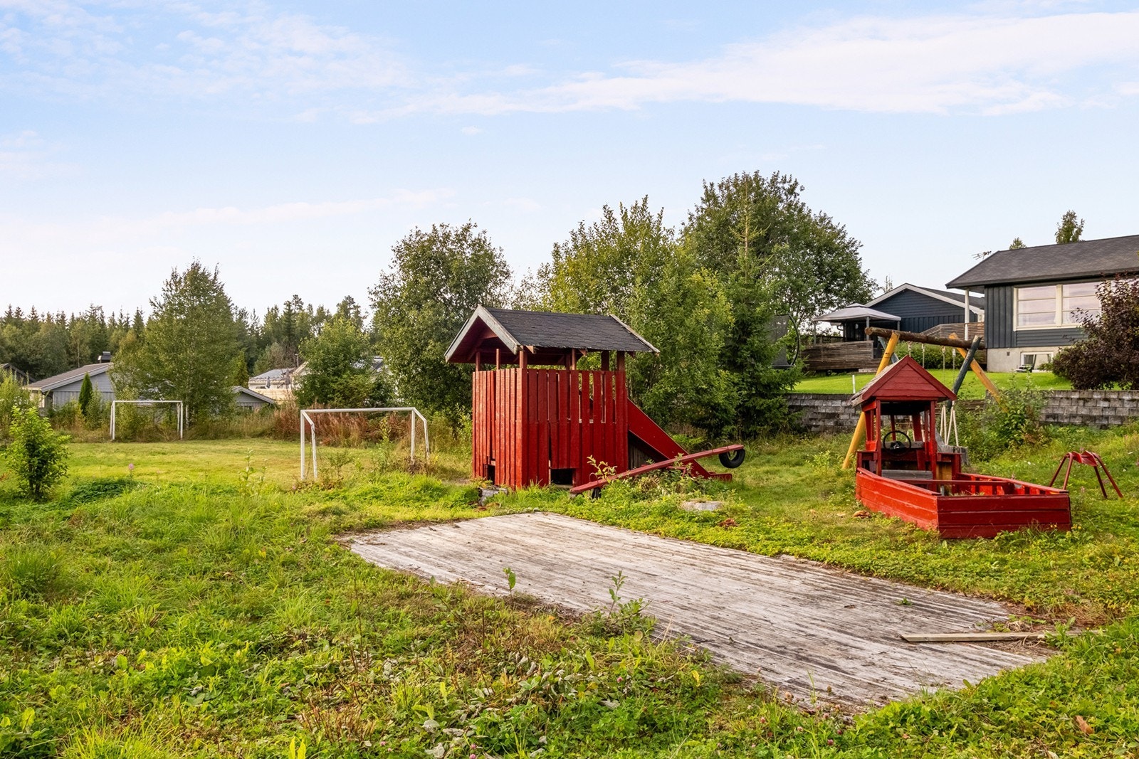 Rett bak tujaene i hagen er det opparbeidet en sti ned til nabolagets lekeplass med mulighet for å starte fotballkarrieren i trygge omgivelser Galleribilde