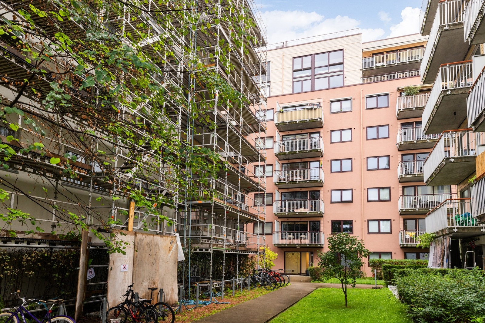 Pene fellesarealer med asfalterte gangveier, gressplen og beplantning omkranser bygget. Galleribilde