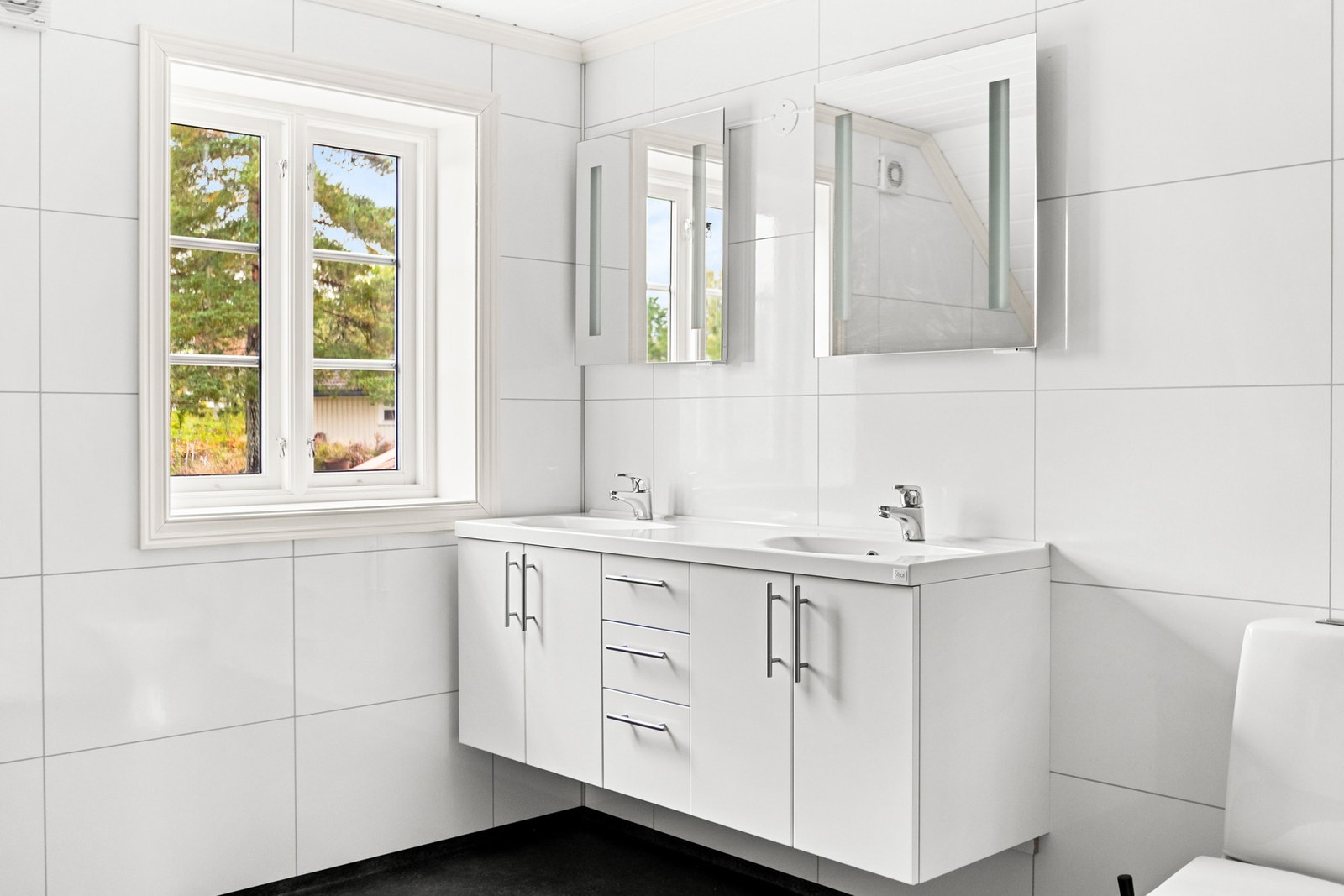 Badet er utstyrt med servant med over- og underskap, dusjkabinett og toalett. Galleribilde