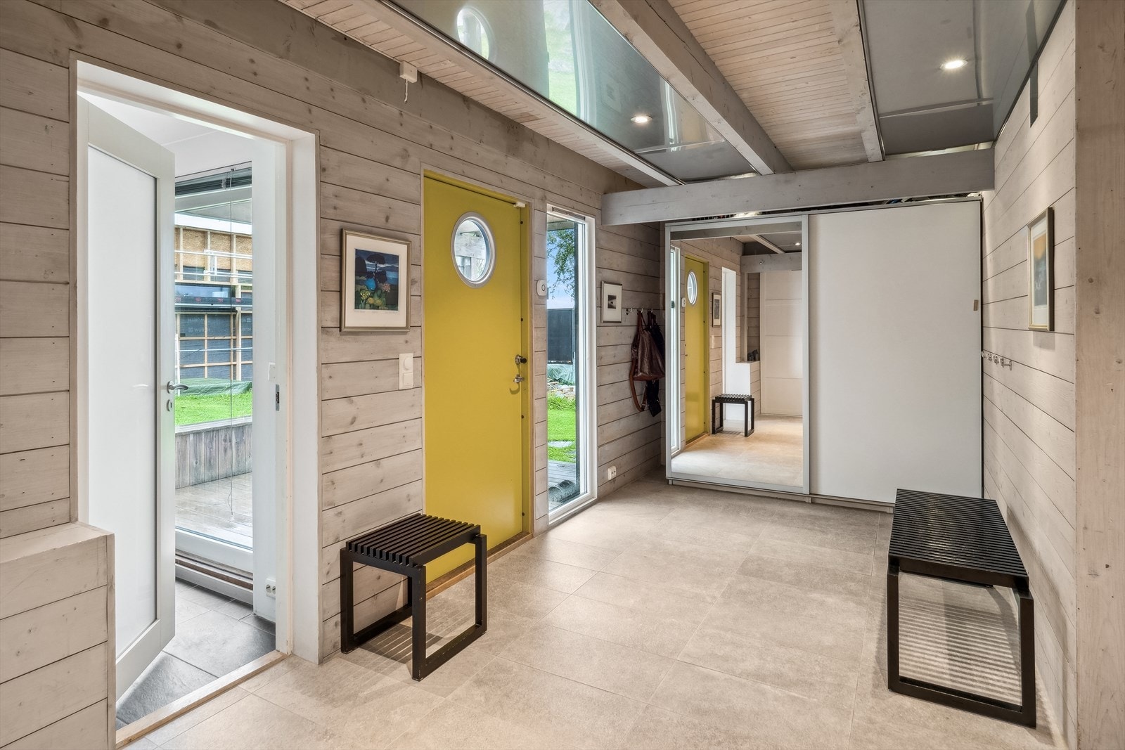 Entré/gang med fliser på gulvet, trepanel på veggene og downlights i himling. To frittstående skyvedørsgarderober gir god plass til sko og yttertøy. Galleribilde