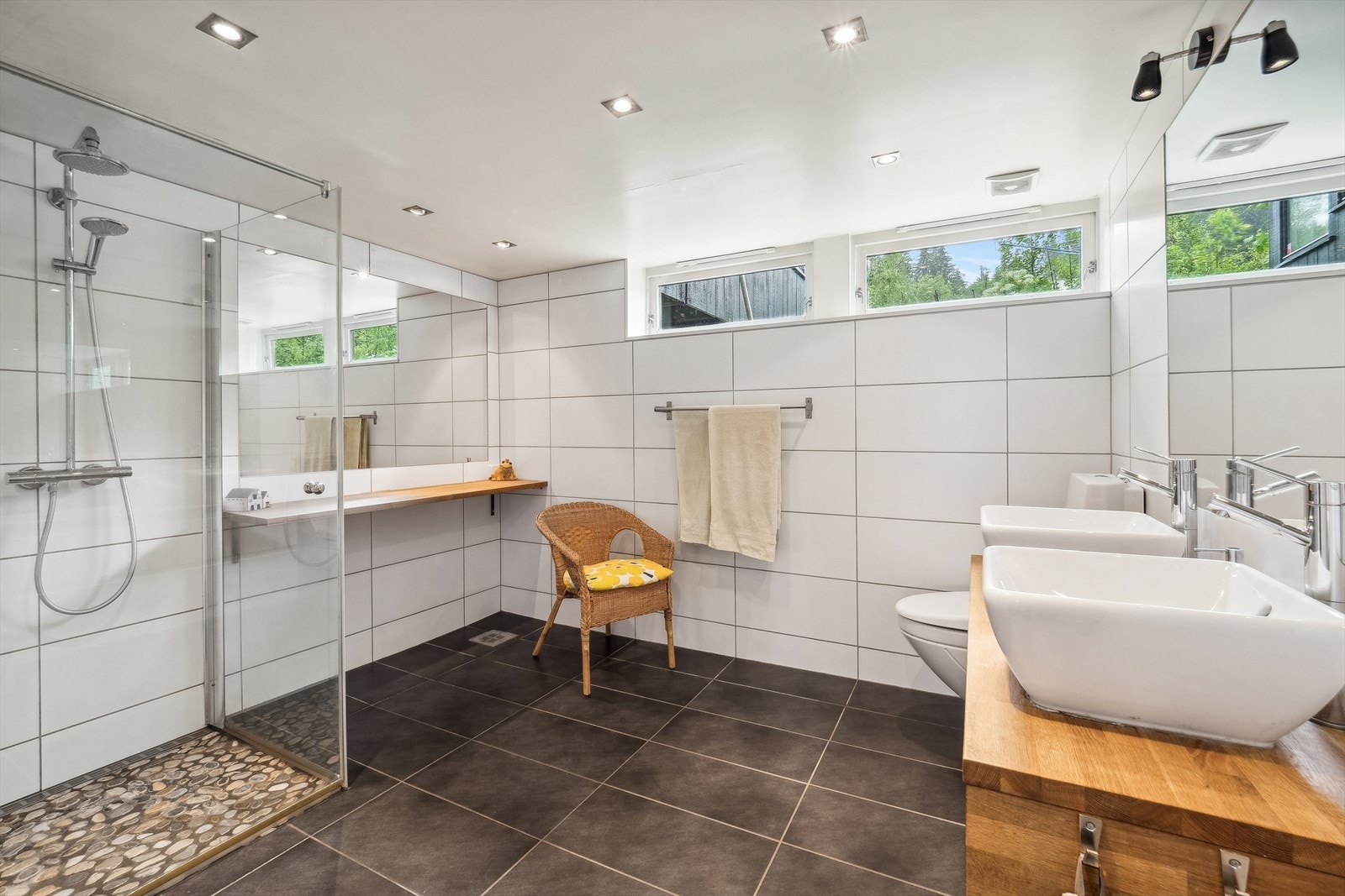 Lekkert bad med lyse fliser på vegger og mørke fliser på gulv med gulvvarme, samt downlights i himling. Galleribilde