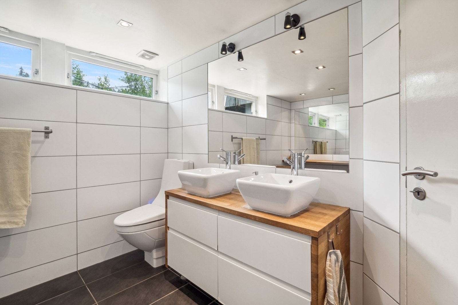 Badet har innredning med dobbelservant med skuffeseksjon, toalett og dusjhjørne, samt fuktstyrt elektrisk vifte. Galleribilde