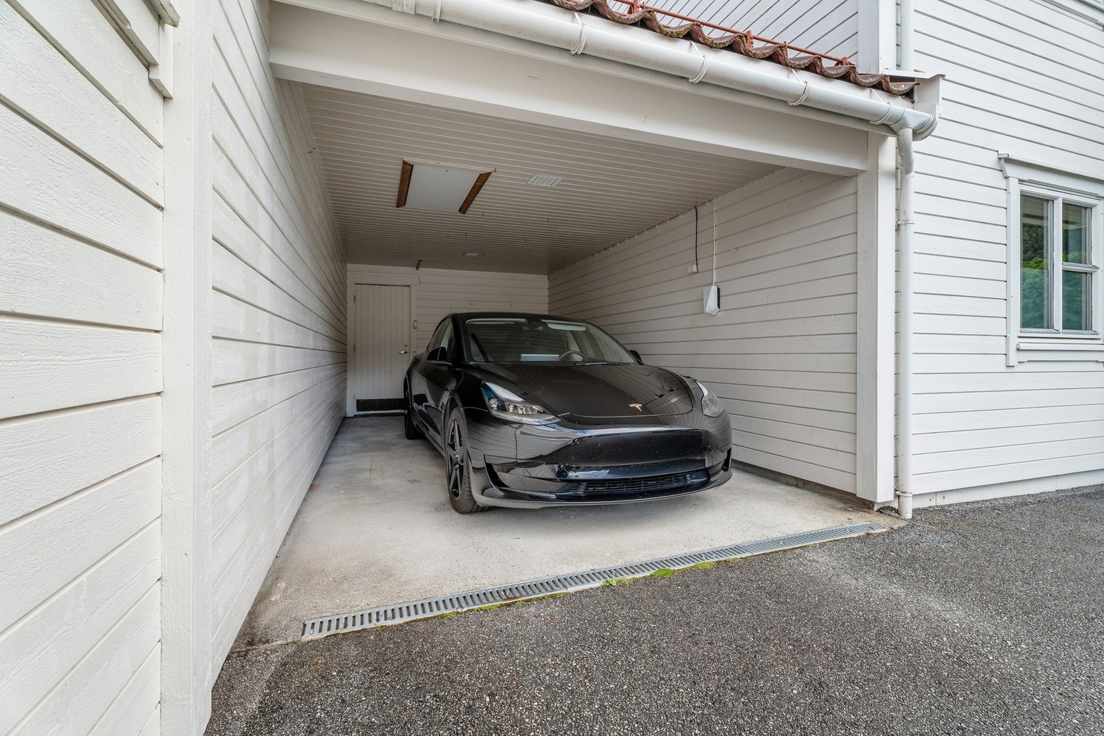 I carporten er det elbil lader montert så sent som i juli 2021. Legg merke til boden i bakkant. Galleribilde