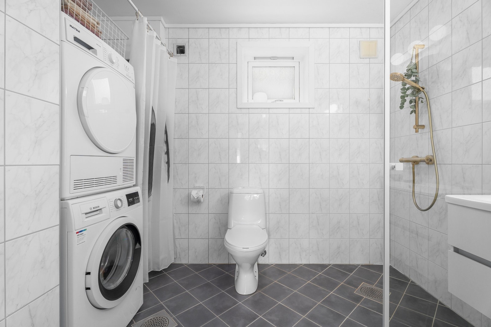 Tilpasset og praktisk nisje for vaskemaskin og tørketrommel, legg også merke til begge slukene i gulvet. Galleribilde