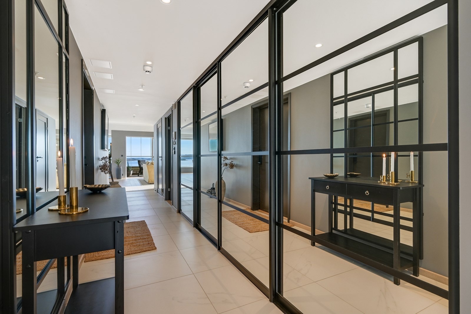 Vel innenfor inngangsdøren møtes man av en romslig og moderne hall. Rommet er gjennomført med lekre fliser i lys marmorutførelse, mørk og lun farge på vegger, og lyst tak. Praktiske garderobeløsninger sikrer god plass til oppbevaring. Galleribilde