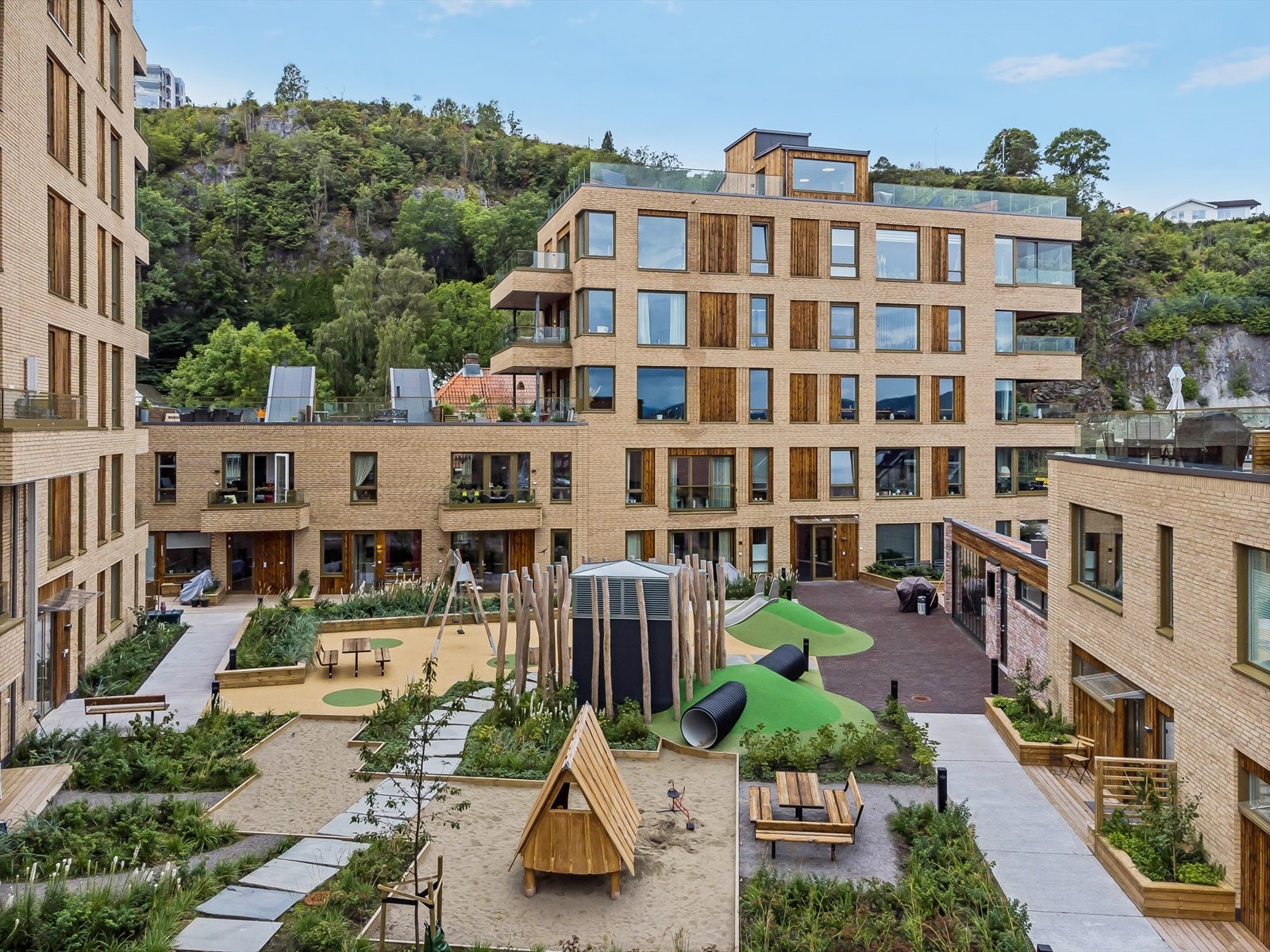 Sameiet har et pent opparbeidet fellesområde med plen, beplanting, lekeapparater og benker. Galleribilde