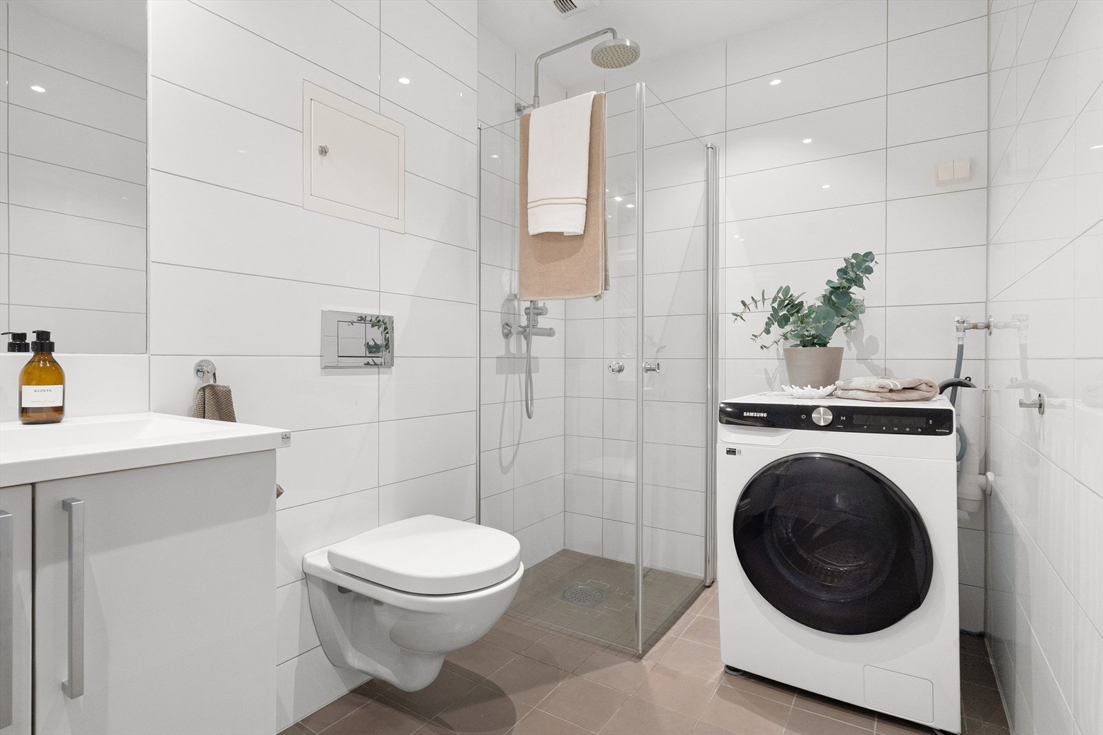 Badet er utstyrt med servantskap med nedfelt servant i møbel og dusjhjørne med glassdører og vegghengt toalett. Galleribilde
