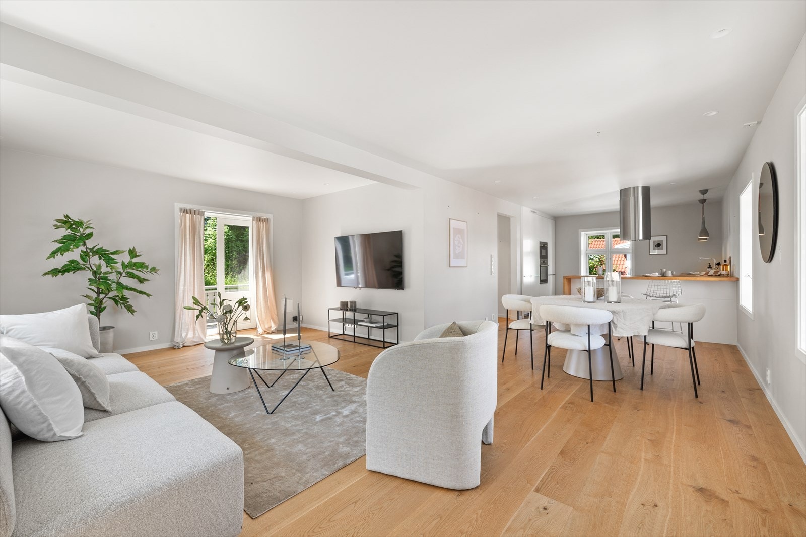 Boligen har en luftig stue med åpen løsning mot kjøkkenet og vinduer i flere retninger som bader rommet i dagslys. Galleribilde