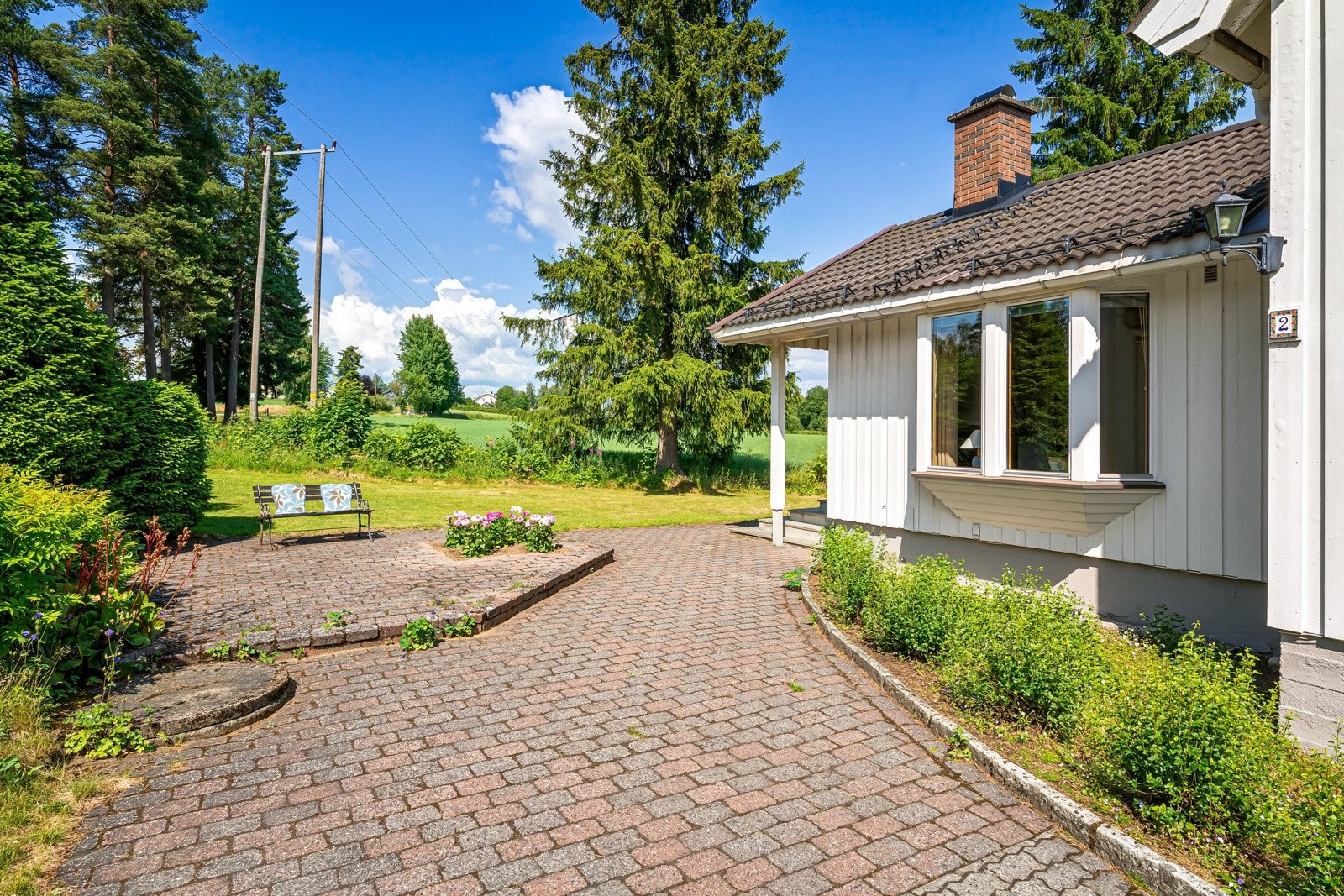 En flott hellelagt gårdsplass med god plass til flere biler. Her sett mot hovedinngang og nord. Galleribilde