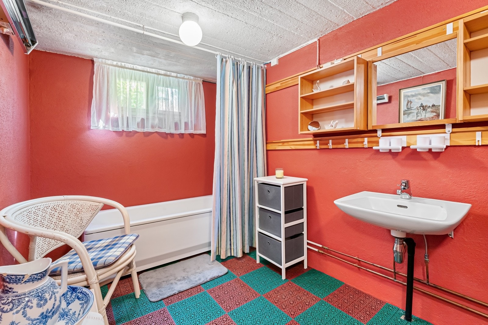 Eldre bad i kjeller etasje. Baderomsinnredning bestående av veggskap. Dusj i badekar, servant og gulvstående klosett. Badet er gitt TG2, foruten himling og inventar som er gitt TG1. Galleribilde