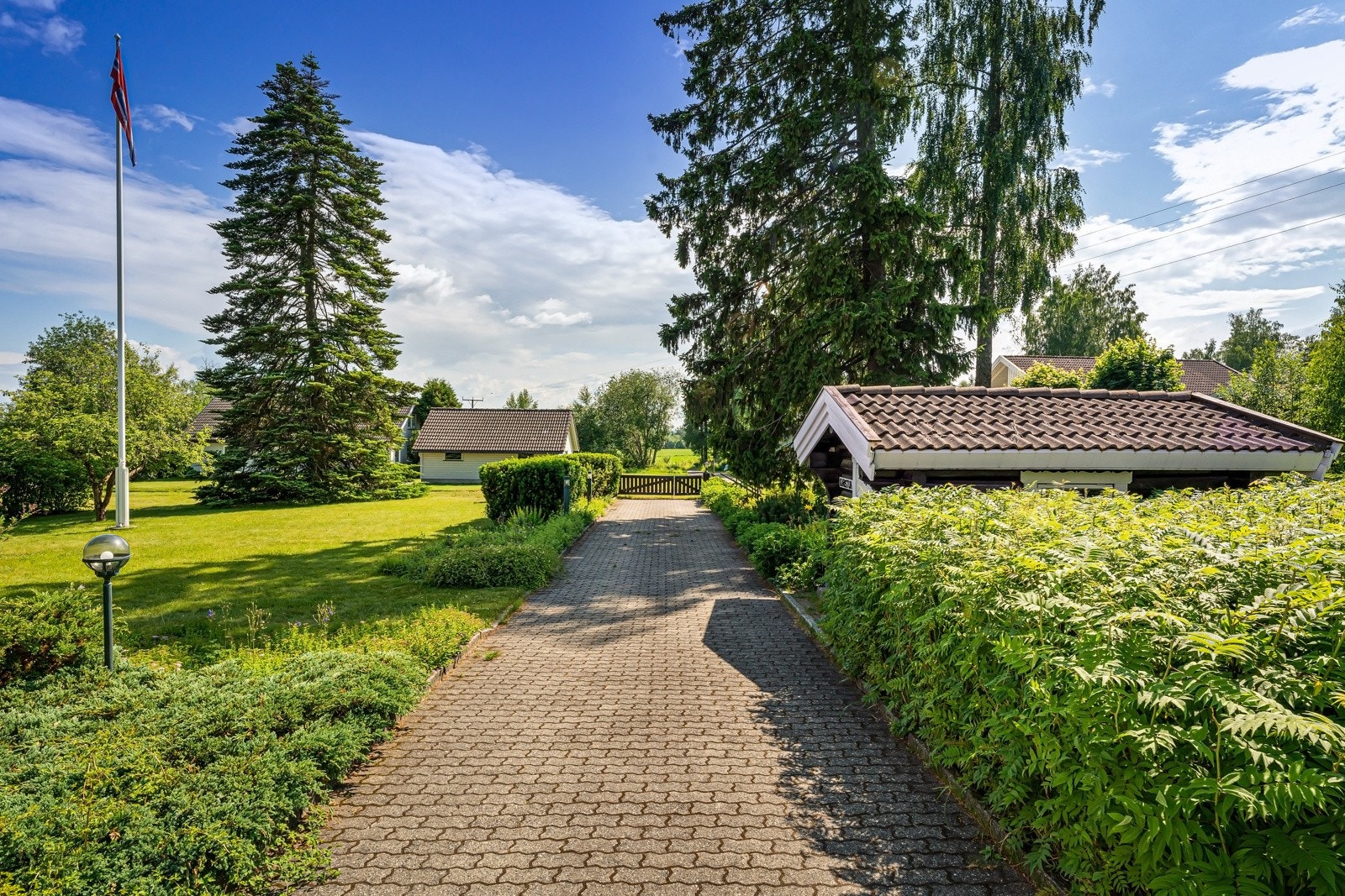 Eiendom sett mot sør og hovedinnkjøring. En flott hellelagt innkjøring. Galleribilde