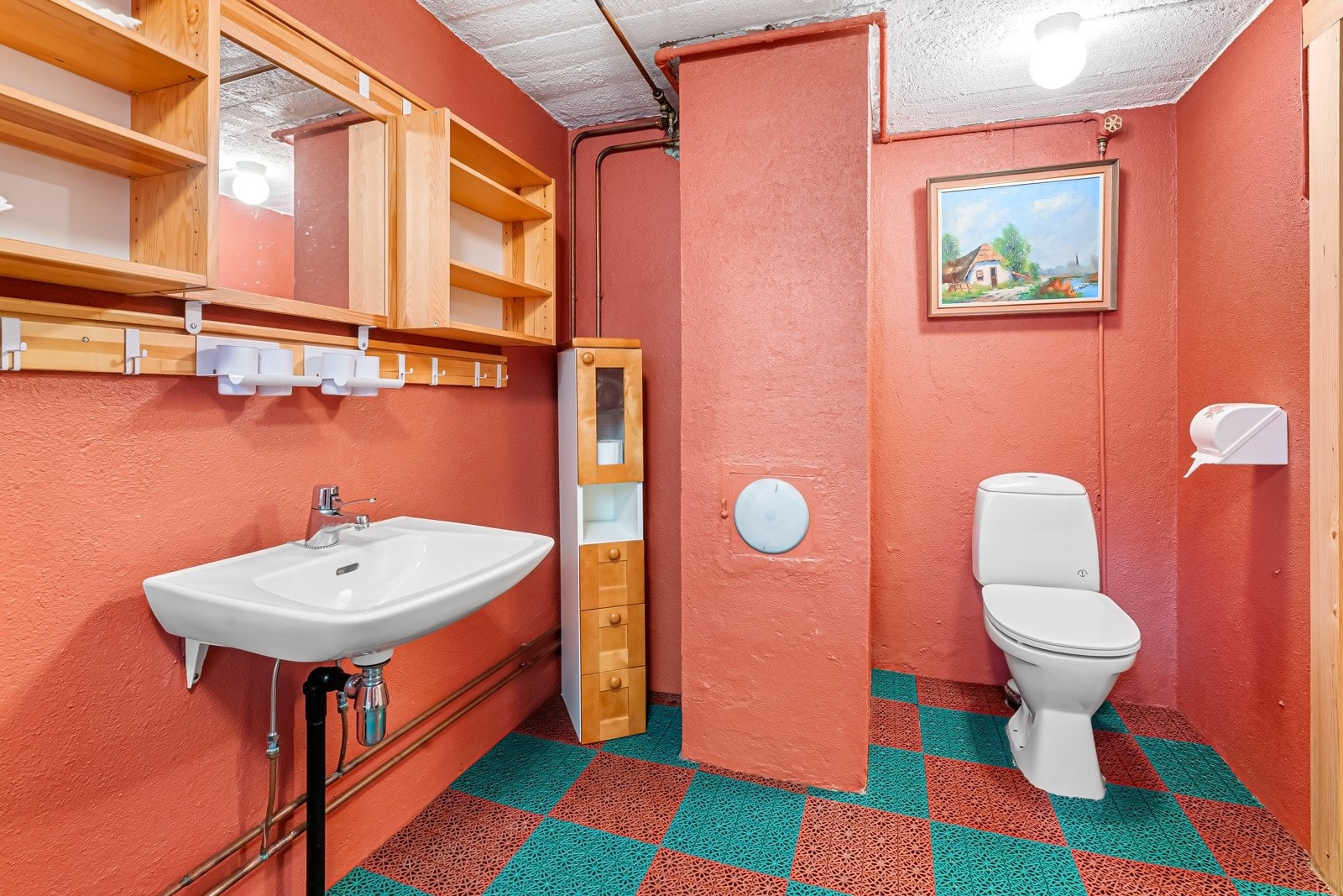 Eldre bad i kjeller etasje. Baderomsinnredning bestående av veggskap. Dusj i badekar, servant og gulvstående klosett. Badet er gitt TG2, foruten himling og inventar som er gitt TG1. Galleribilde