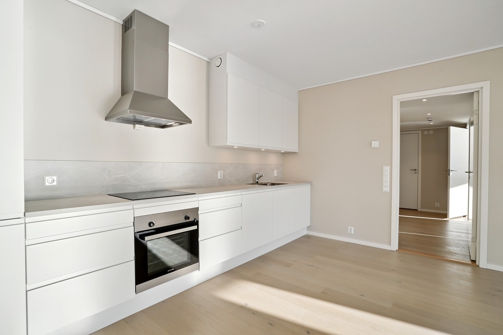 Kjøkkenet er levert med hvite glatte fronter med grepskant og dempet lukking. Benkeplate med oppkant for et eksklusivt preg. Galleribilde