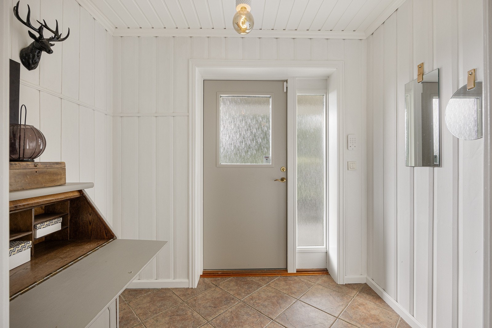 Boligen har en lys og fin entré med hvitmalt panel på veggene og sandfargede fliser på gulv med vannbåren gulvvarme. Galleribilde