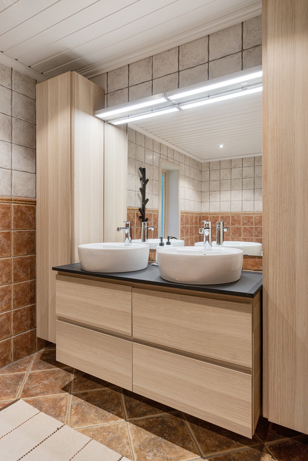 På badet i 1. etasje er det to lyse høyskap og en bred, lys skuffeseksjon med to toppmonterte, runde servanter. Galleribilde